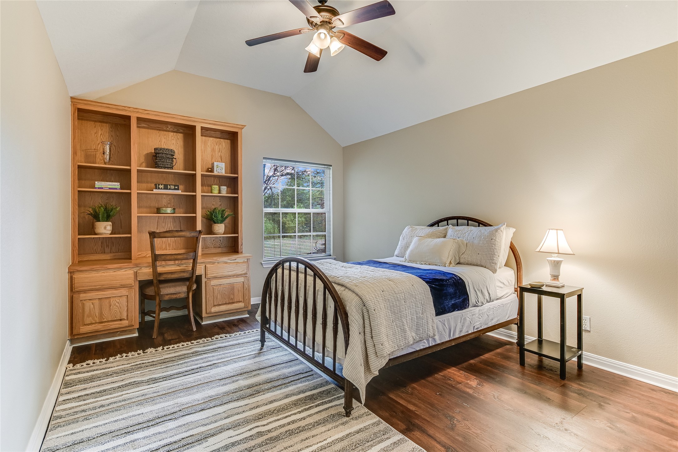 741 Knobbs Road McDade, TX 78650 - Photo 20 of 38 A restful retreat features built-in shelving, hardwood floors, and a vaulted ceiling with a fan.