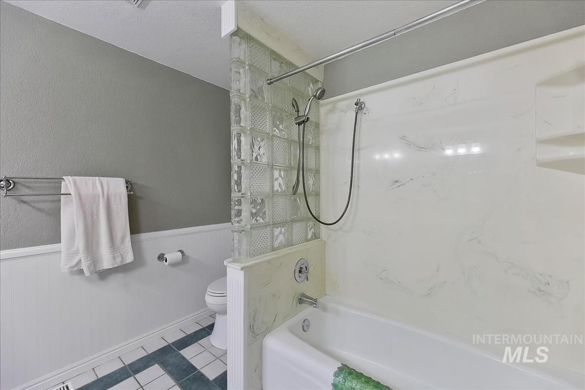 11875 West Hidden Valley Rim Road Boise, ID 83709 - Photo 23 of 36 Bathroom featuring a wainscoted wall, bathtub / shower combination, tile patterned flooring, a textured wall, and a textured ceiling