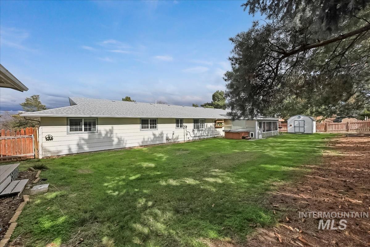 11875 West Hidden Valley Rim Road Boise, ID 83709 - Photo 33 of 36 Rear view of house with a fenced backyard, a shed, a hot tub, roof with shingles, and a sunroom