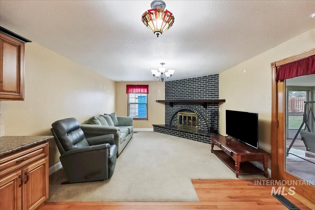 11875 West Hidden Valley Rim Road Boise, ID 83709 - Photo 4 of 36 Living room featuring a textured ceiling, a brick fireplace, hanging lights, and light wood-style flooring