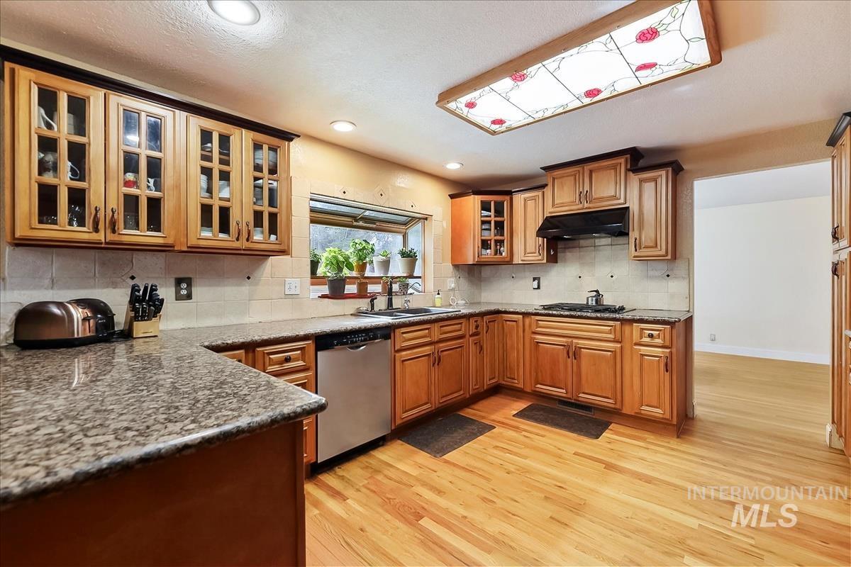 11875 West Hidden Valley Rim Road Boise, ID 83709 - Photo 7 of 36 Kitchen featuring glass insert cabinets, light wood-style floors, stainless steel dishwasher, wood finish cabinetry, and recessed lighting