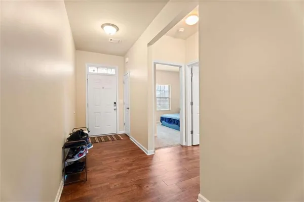a view of a hallway with wooden floor and a bathroom