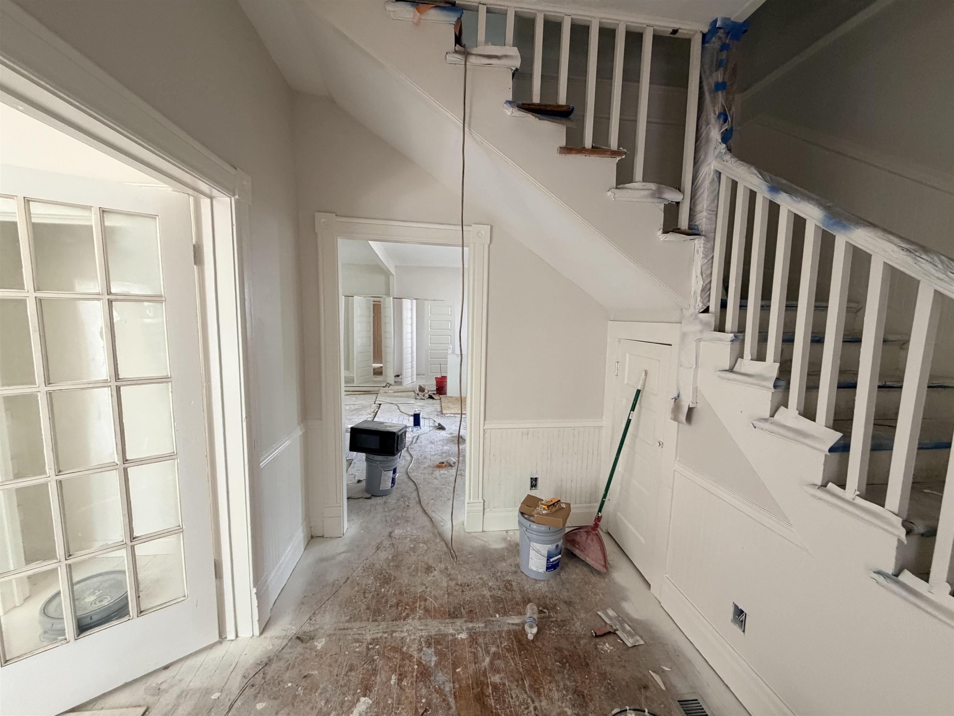 961 Meda Street Memphis, TN 38104 - Photo 5 of 27 Staircase with painted wood banister, beadboard wainscoting, and French doors featuring multiple glass panes