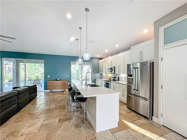 a large kitchen with kitchen island a refrigerator a stove a sink a dining table and chairs with wooden floor
