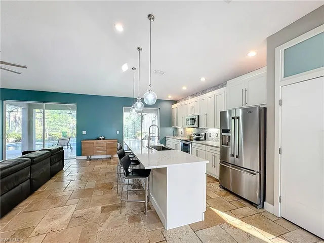 a large kitchen with kitchen island a refrigerator a stove a sink a dining table and chairs with wooden floor