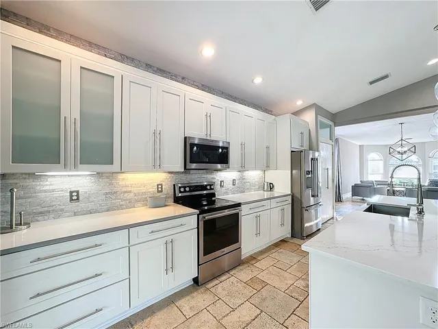 a kitchen with a sink white cabinets and stainless steel appliances