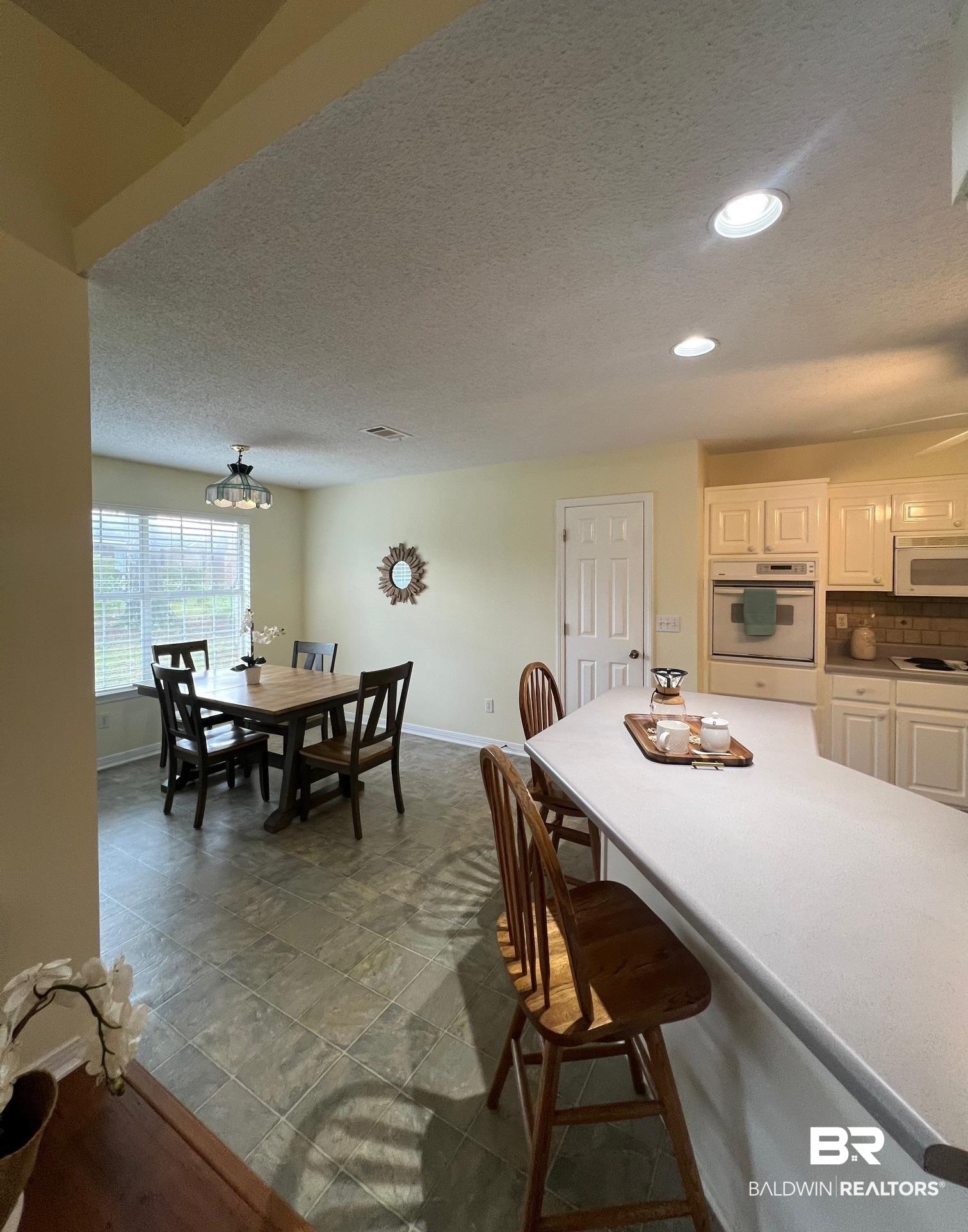 2204 Club House Drive Lillian, AL 36549 - Photo 6 of 38 Kitchen featuring white appliances, a kitchen breakfast bar, white cabinetry, recessed lighting, and a textured ceiling