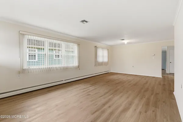 an empty room with wooden floor and windows