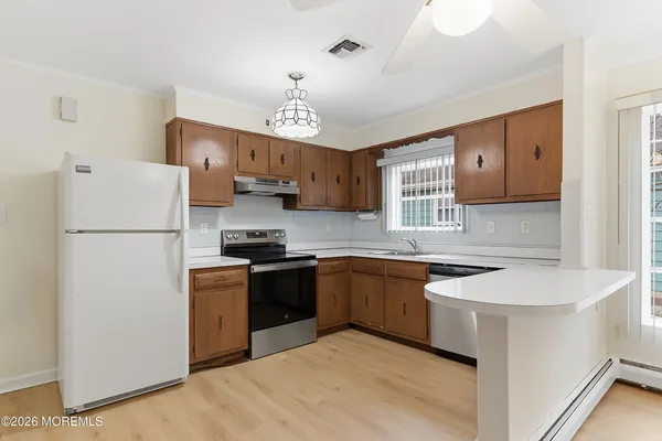 a kitchen with stainless steel appliances granite countertop a refrigerator a sink dishwasher a stove and white cabinets with wooden floor