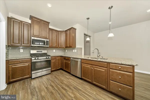 a kitchen with stainless steel appliances granite countertop a sink a stove and a wooden floors