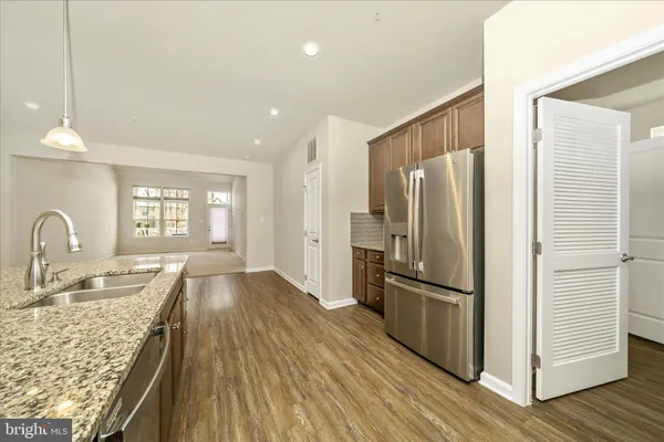 a kitchen with granite countertop a refrigerator oven a sink dishwasher and wooden cabinets with wooden floor