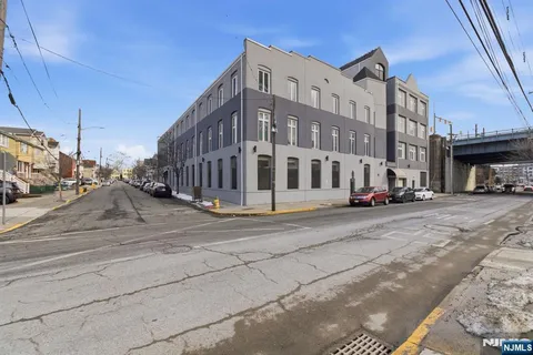 a front view of a building with lot of cars and trees