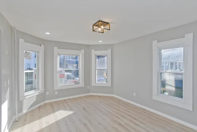 a view of an empty room with a window and wooden floor