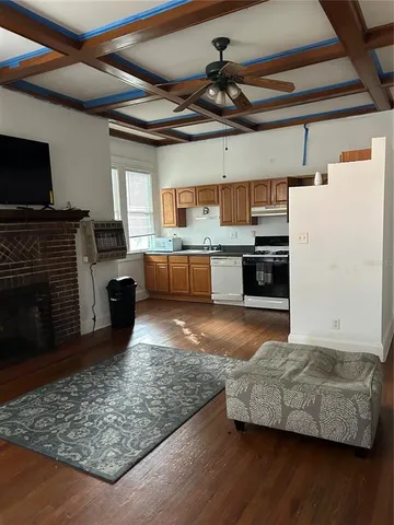 a living room with stainless steel appliances granite countertop furniture wooden floor and a fireplace
