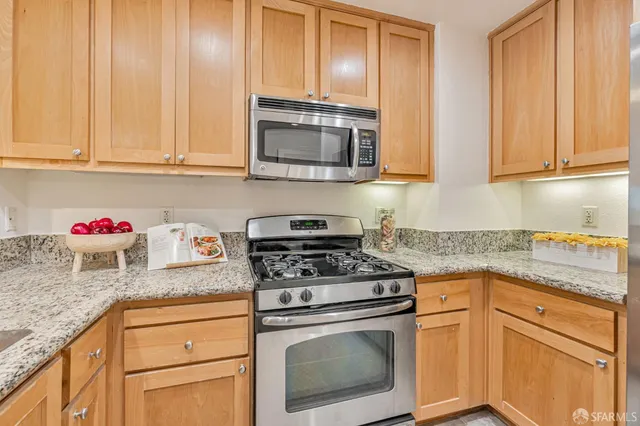 a kitchen with granite countertop white cabinets and stainless steel appliances