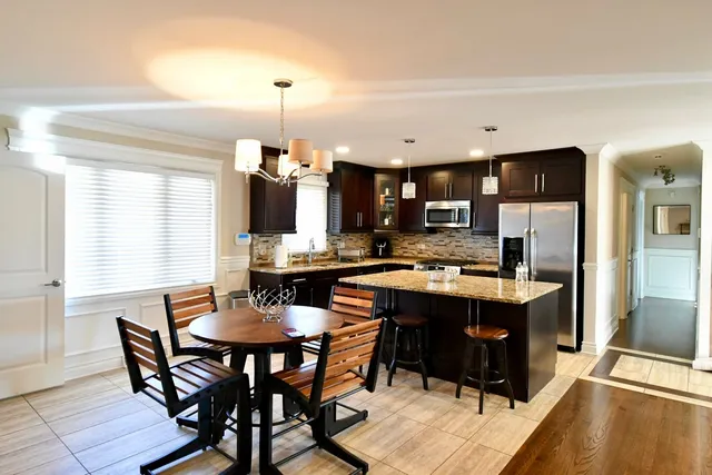 a kitchen with a dining table chairs and refrigerator