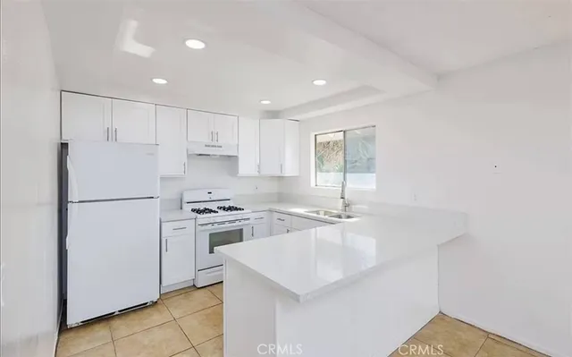 a kitchen with a sink a stove a refrigerator and white cabinets