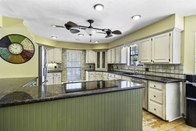 a kitchen with stainless steel appliances kitchen island granite countertop a refrigerator a oven a sink and dishwasher with wooden floor