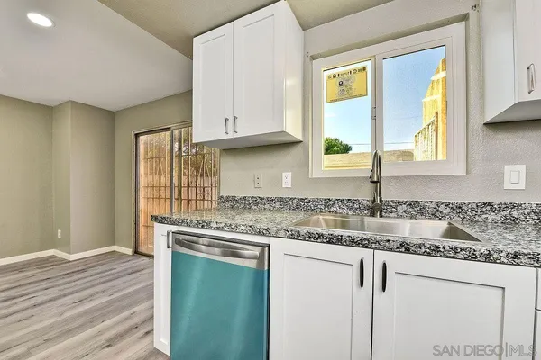 a kitchen with granite countertop white cabinets and a window
