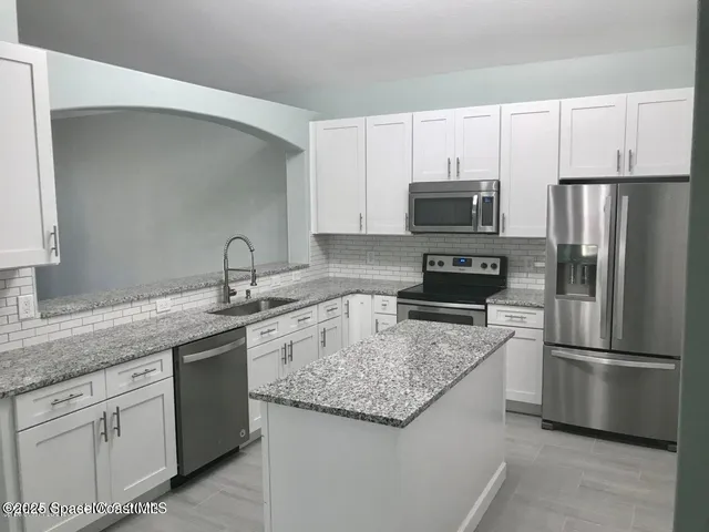 a kitchen with appliances a sink and cabinets
