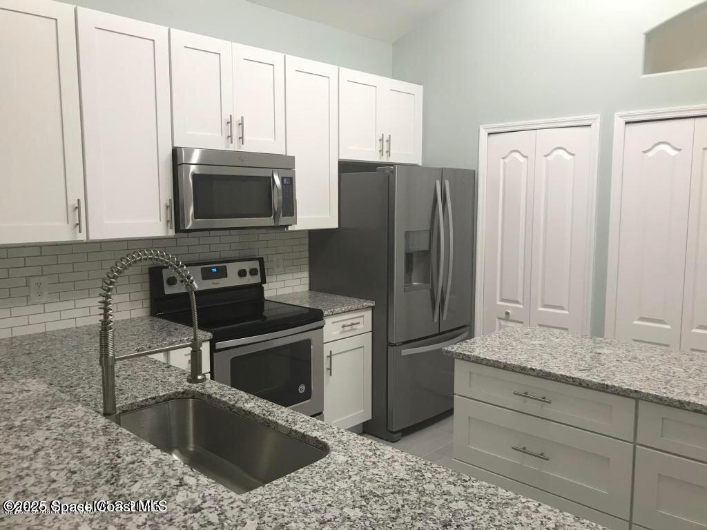 3121 Atocha Lane Indialantic, FL 32903 - Photo 3 of 17 a kitchen with stainless steel appliances granite countertop a refrigerator a stove a sink and white cabinets