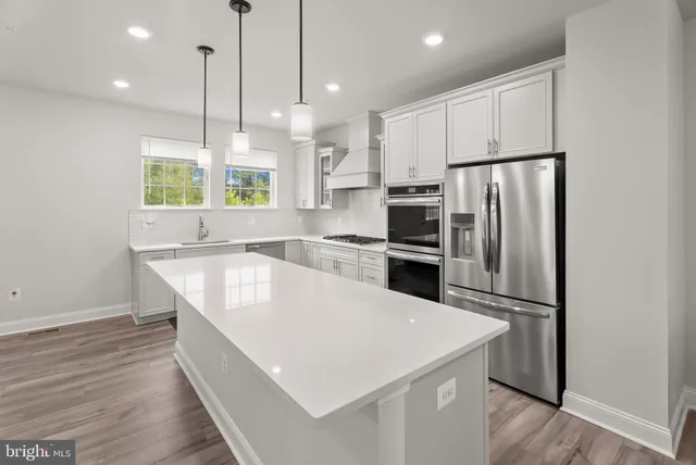 a large kitchen with stainless steel appliances granite countertop a refrigerator a sink dishwasher a stove and a refrigerator with wooden floor