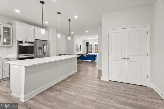 a large white kitchen with a large counter top stainless steel appliances and wooden floor