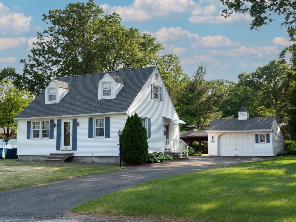 a front view of a house with a garden and trees