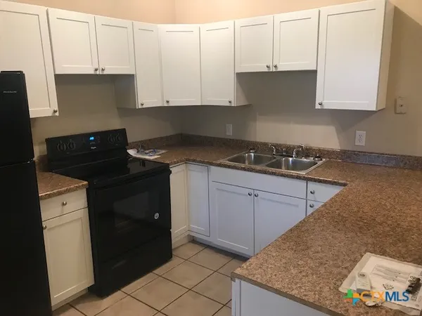 a kitchen with granite countertop white cabinets and black appliances
