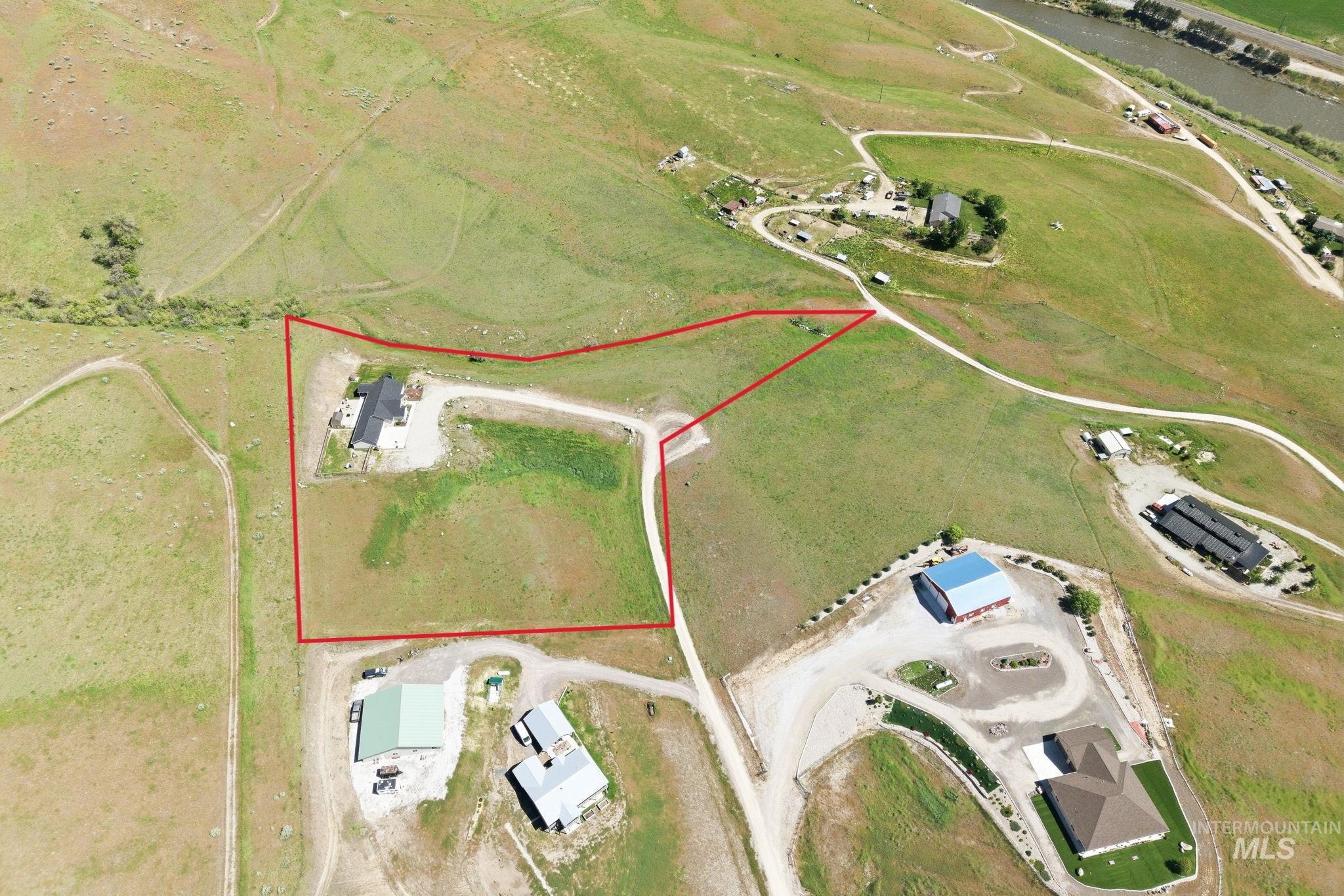 25 River Ridge Horseshoe Bend, ID 83629 - Photo 12 of 50 Expansive land parcel featuring a contemporary residence with a dark roof, surrounded by natural grasslands and an unpaved driveway