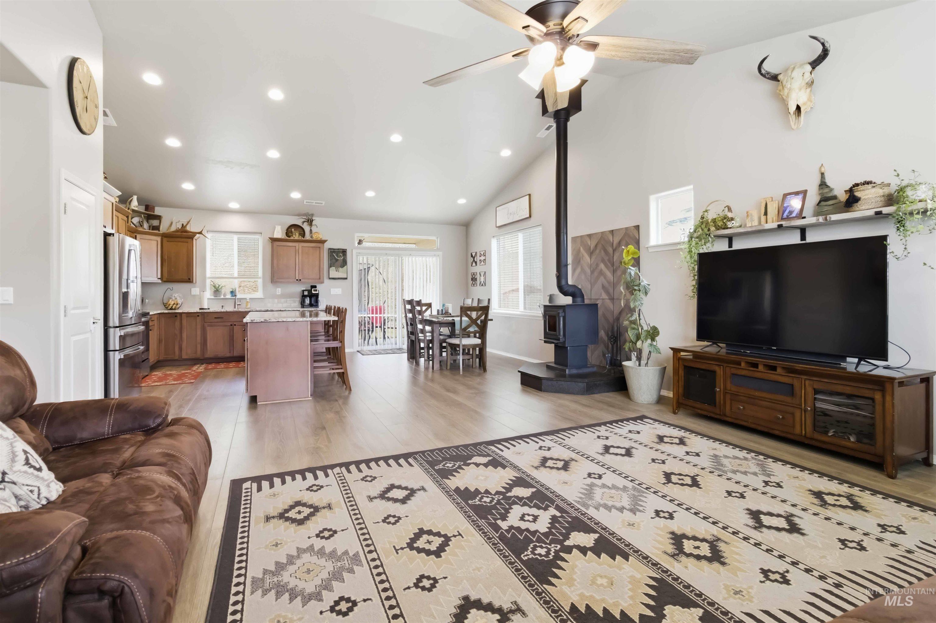 25 River Ridge Horseshoe Bend, ID 83629 - Photo 18 of 50 Living room with a wood stove, light wood finished floors, vaulted ceiling, recessed lighting, and a ceiling fan