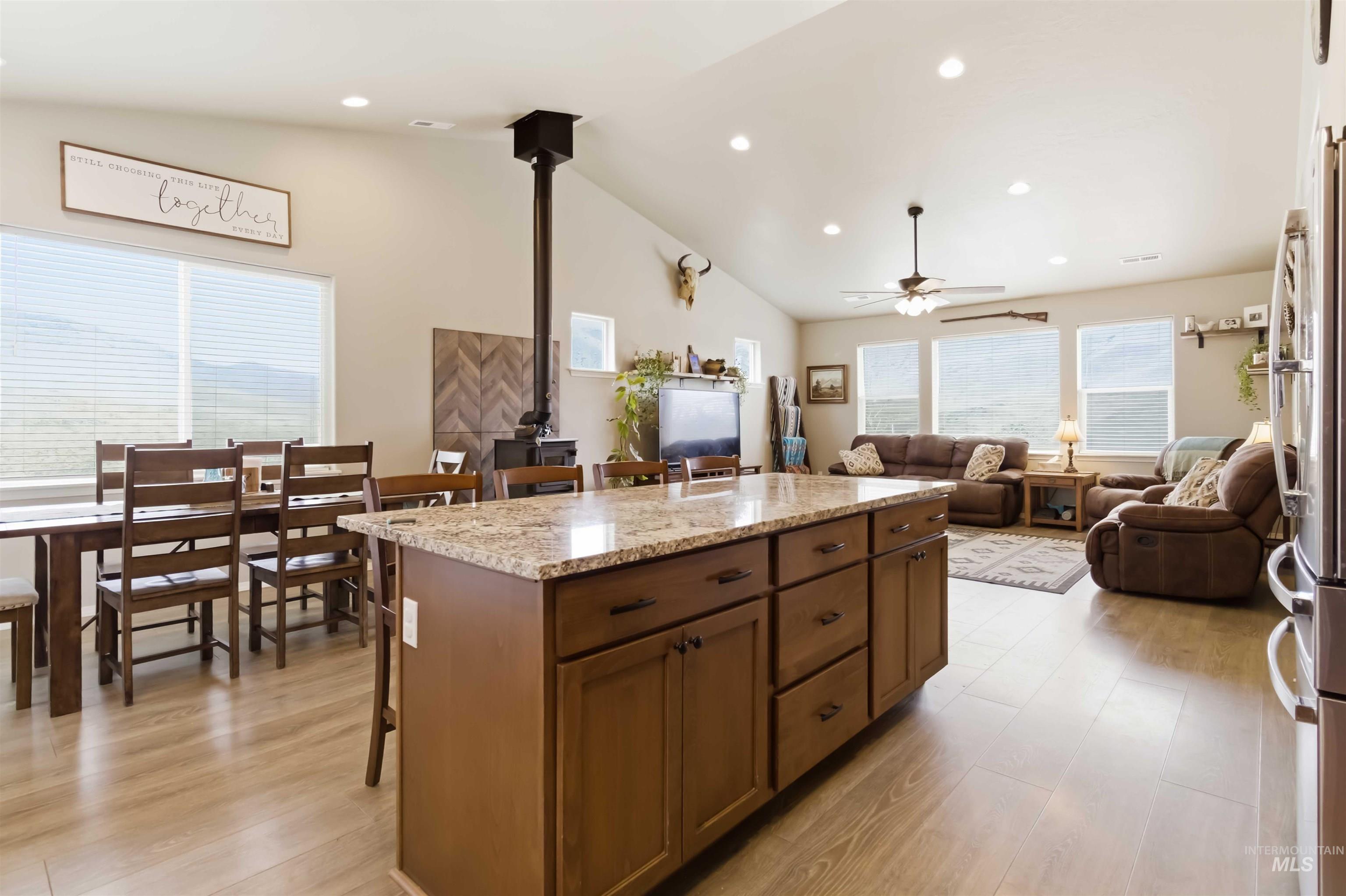 25 River Ridge Horseshoe Bend, ID 83629 - Photo 19 of 50 Kitchen featuring a breakfast bar, a wood stove, light stone counters, light wood-type flooring, and vaulted ceiling