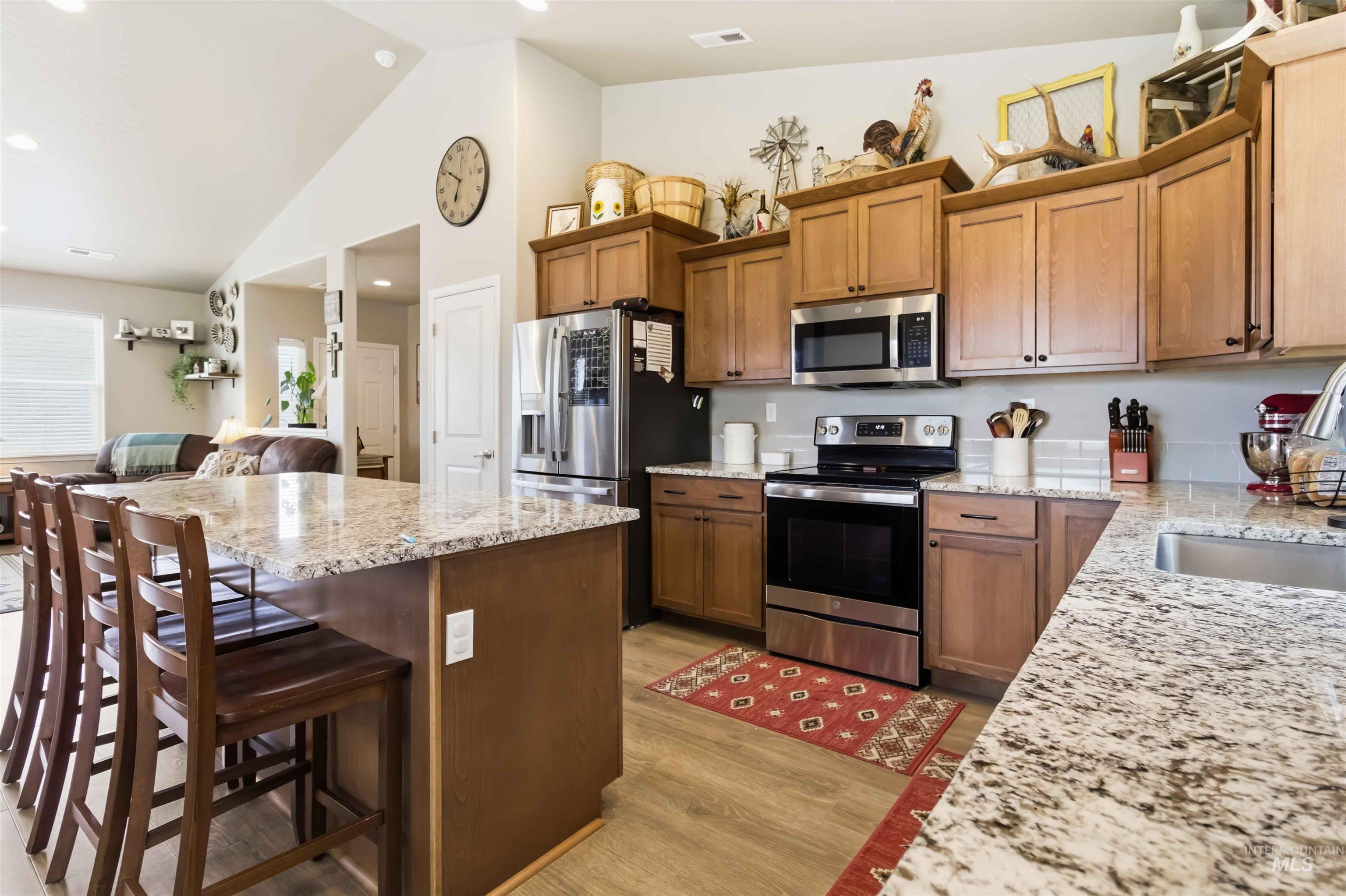 25 River Ridge Horseshoe Bend, ID 83629 - Photo 50 of 50 Kitchen with stainless steel appliances, open floor plan, light stone countertops, wood finish cabinets, and lofted ceiling