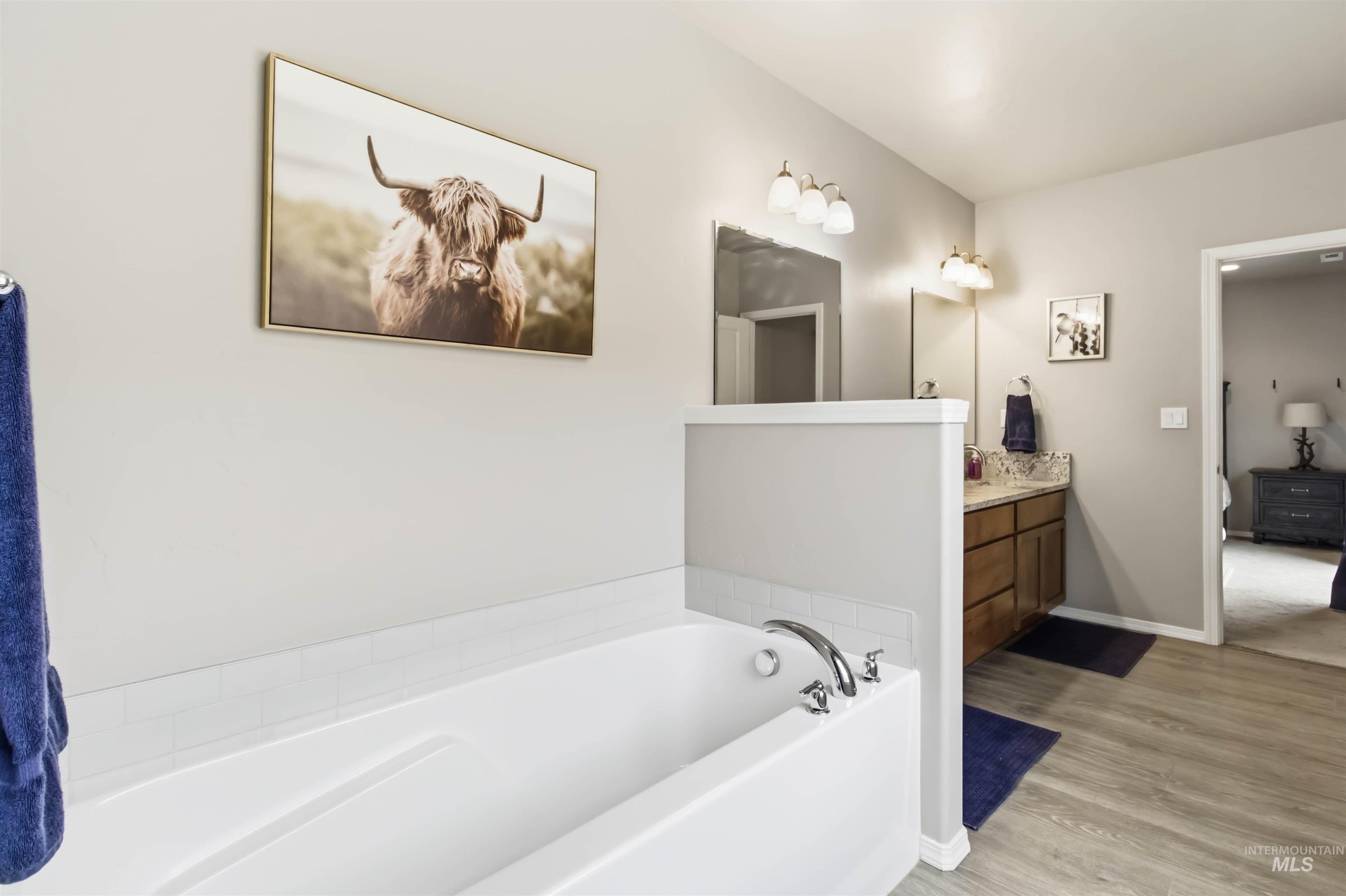 25 River Ridge Horseshoe Bend, ID 83629 - Photo 24 of 50 Full bathroom featuring vanity, a garden tub, light wood-type flooring, and connected bathroom