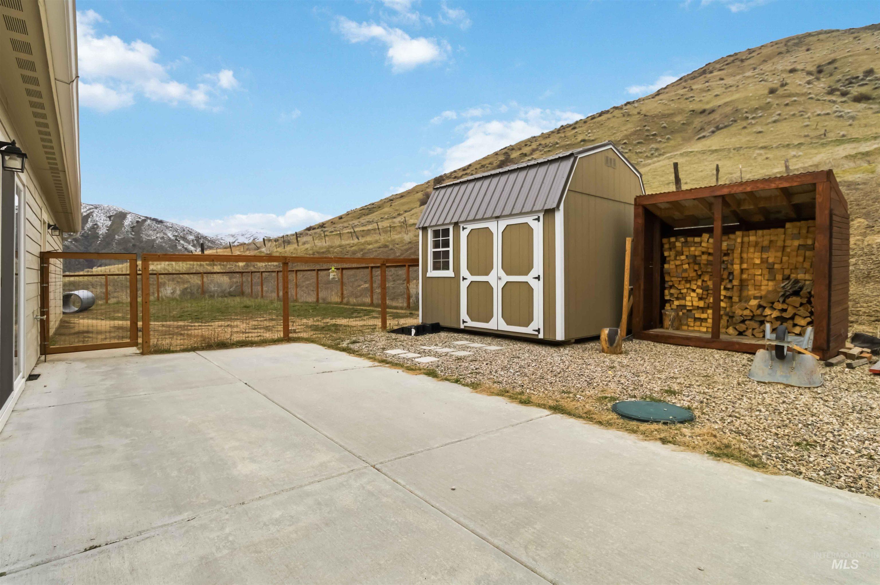 25 River Ridge Horseshoe Bend, ID 83629 - Photo 39 of 50 Fenced backyard featuring a storage unit, a mountain view, and a patio