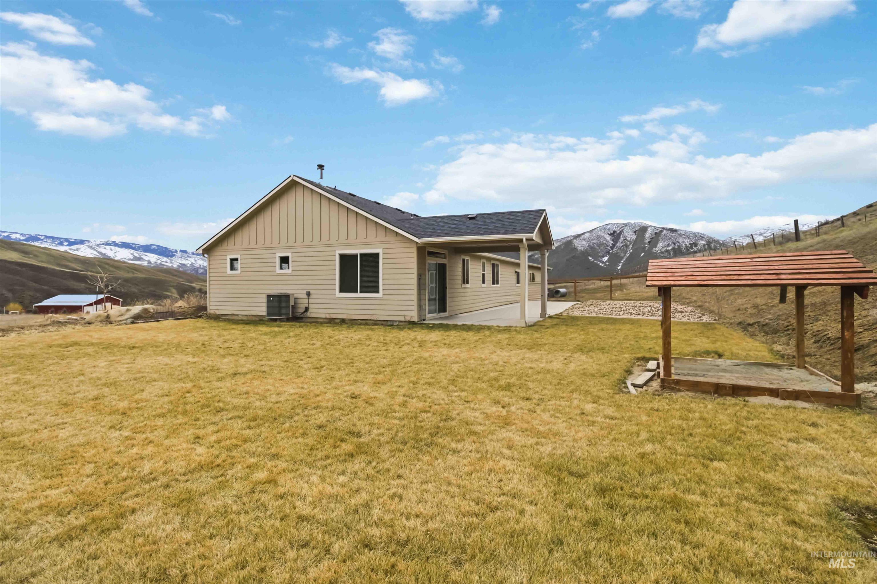 25 River Ridge Horseshoe Bend, ID 83629 - Photo 42 of 50 Rear view of house with a mountain view, a patio area, board and batten siding, a lawn, and roof with shingles
