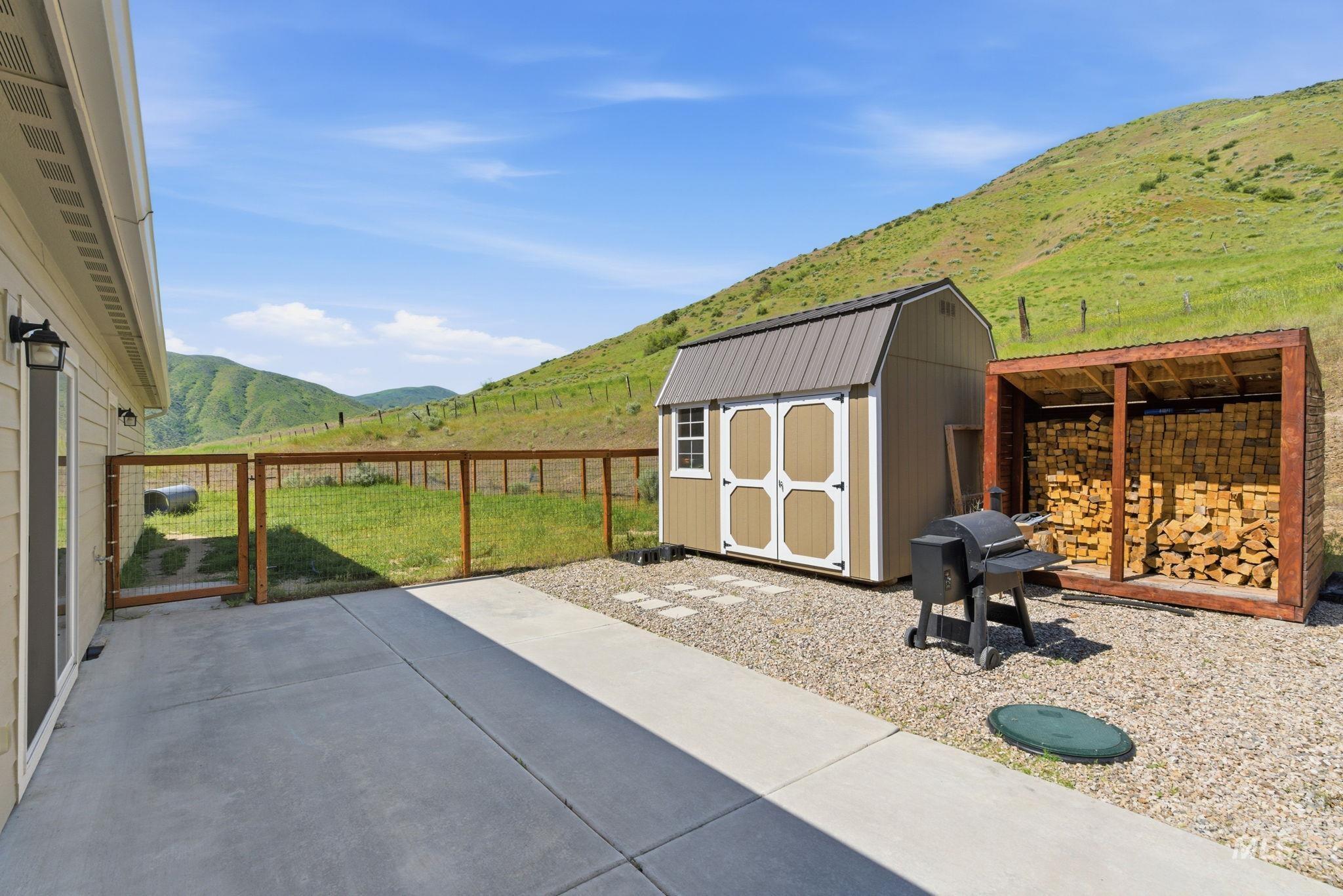 25 River Ridge Horseshoe Bend, ID 83629 - Photo 45 of 50 Spacious concrete patio with gravel landscaping, a durable storage shed, and a dedicated wood storage structure