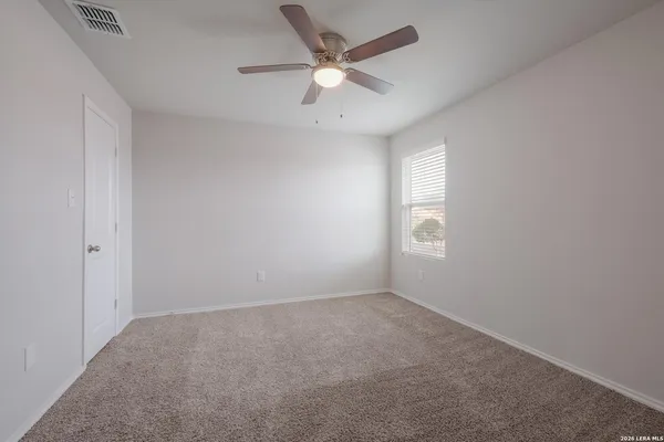 an empty room with a window and a fan
