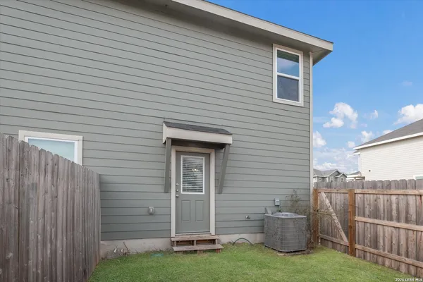 a view of backyard of a house with wooden fence