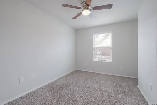 an empty room with a window and a fan