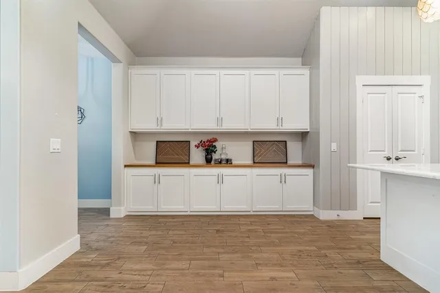 a kitchen with a sink dishwasher a stove and white cabinets with wooden floor