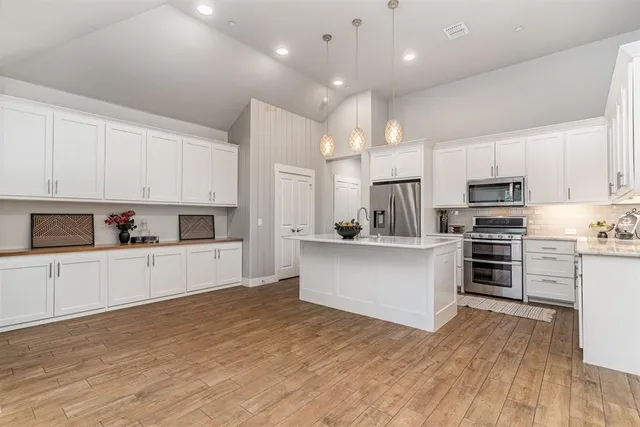 a large kitchen with cabinets wooden floor and stainless steel appliances