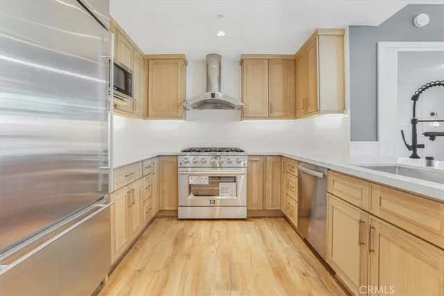 a large kitchen with stainless steel appliances granite countertop a sink and cabinets with wooden floor