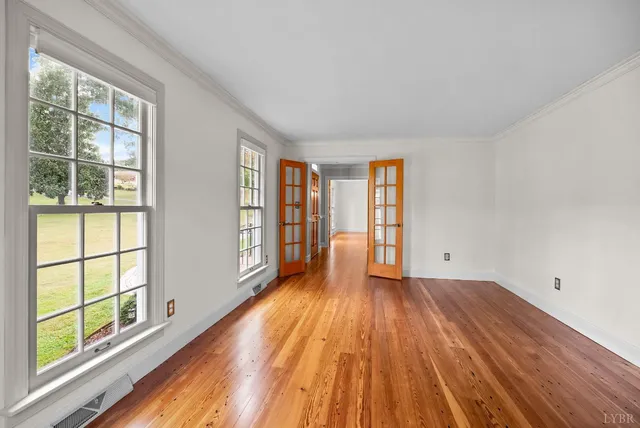 a view of a room with wooden floor ceiling fan and windows