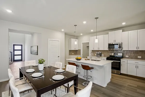 a kitchen with stainless steel appliances kitchen island granite countertop a dining table and chairs