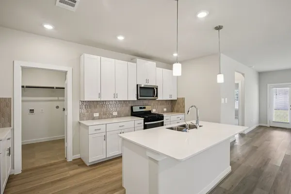 a kitchen with a sink a stove a refrigerator and white cabinets