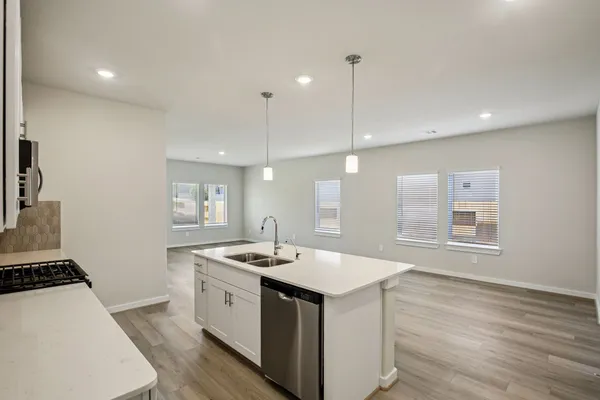 a kitchen with a sink stove and wooden floor