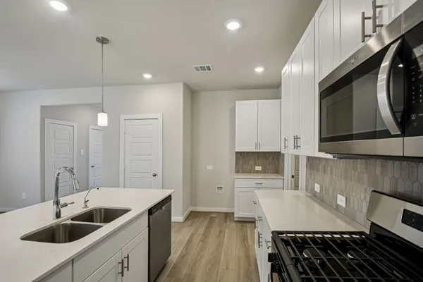 a kitchen with stainless steel appliances granite countertop a sink a stove and a wooden floors