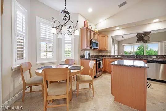 a dining room with stainless steel appliances kitchen island granite countertop a table and chairs in it