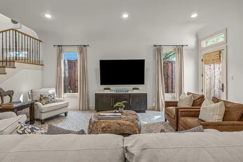 a living room with furniture a flat screen tv and a chandelier